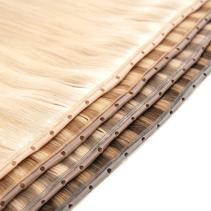 Extreme close-up of premium 100% virgin remy cuticle human hair butterfly weft extensions with pre-punched holes in blonde and brown shades for B2B wholesale salons and brands.